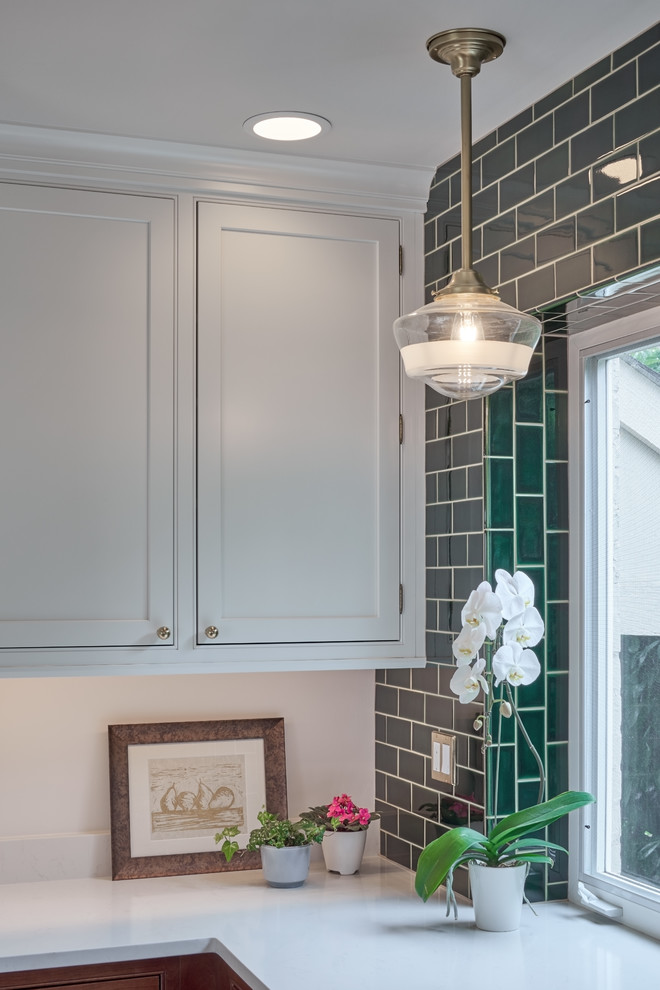 Kitchen - mid-sized transitional u-shaped medium tone wood floor kitchen idea in Seattle with a farmhouse sink, beaded inset cabinets, white cabinets, quartz countertops, green backsplash, porcelain backsplash, stainless steel appliances and white countertops