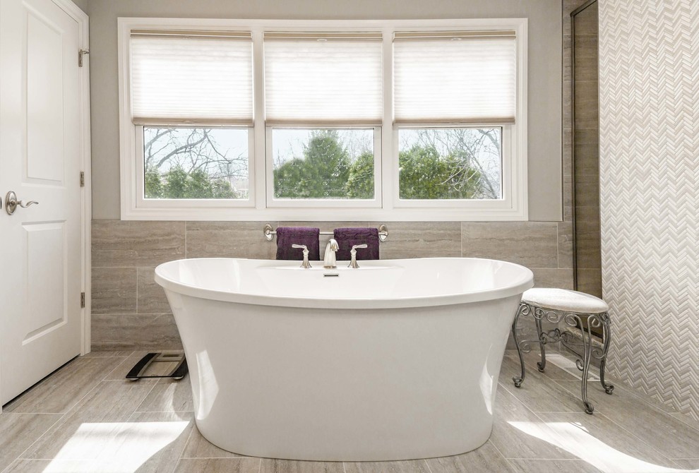 Example of a large transitional master brown tile, beige tile and porcelain tile porcelain tile and beige floor freestanding bathtub design in Chicago with raised-panel cabinets, white cabinets, beige walls, an undermount sink, granite countertops, a hinged shower door and beige countertops