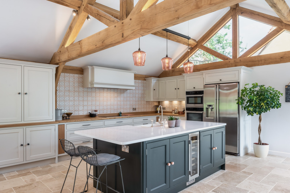 Inspiration for a transitional u-shaped open plan kitchen in Other with a farmhouse sink, recessed-panel cabinets, white cabinets, wood benchtops, multi-coloured splashback, stainless steel appliances, with island, multi-coloured floor, brown benchtop, exposed beam and vaulted.