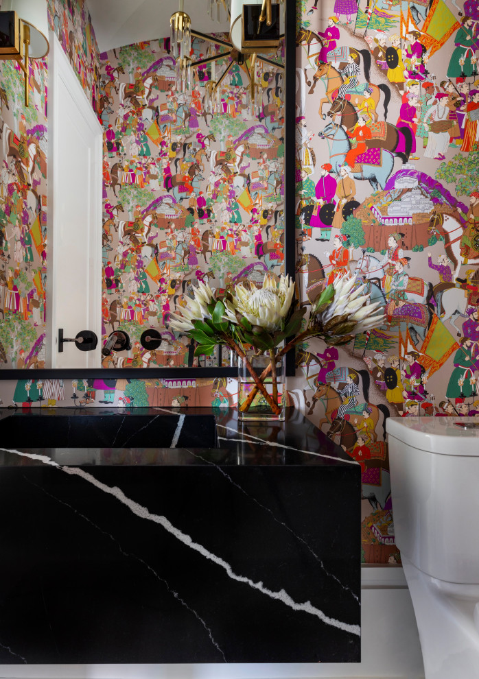 Réalisation d'un WC et toilettes tradition de taille moyenne avec des portes de placard noires, un mur multicolore, sol en stratifié, un plan de toilette en marbre, un plan de toilette noir, meuble-lavabo suspendu et du papier peint.