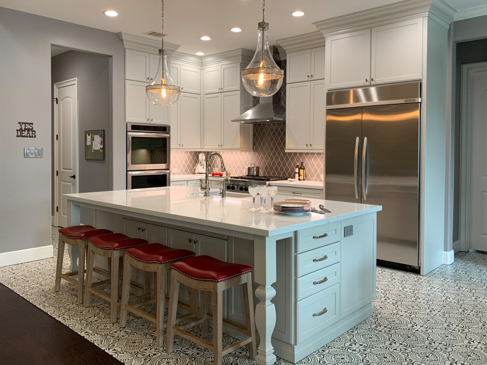 Example of a transitional l-shaped porcelain tile and multicolored floor kitchen design in Houston with a farmhouse sink, recessed-panel cabinets, white cabinets, quartz countertops, gray backsplash, ceramic backsplash, stainless steel appliances, an island and white countertops