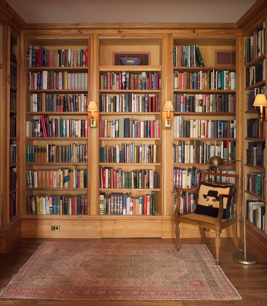 This is an example of a traditional family room in New York with a library and medium hardwood floors.