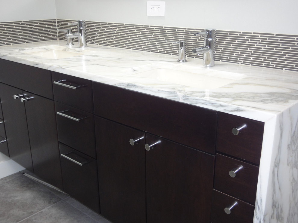 Inspiration for a mid-sized contemporary master bathroom in Seattle with an undermount sink, flat-panel cabinets, dark wood cabinets, marble benchtops, a drop-in tub, a corner shower, gray tile, matchstick tile, grey walls and porcelain floors.