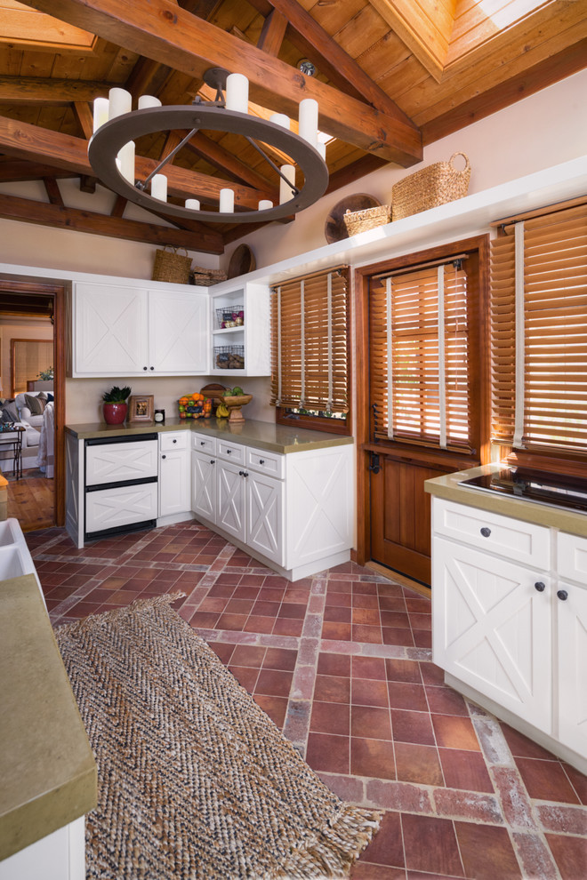 This is an example of a mid-sized galley separate kitchen in San Diego with a farmhouse sink, raised-panel cabinets, white cabinets, concrete benchtops, beige splashback, white appliances, terra-cotta floors and no island.