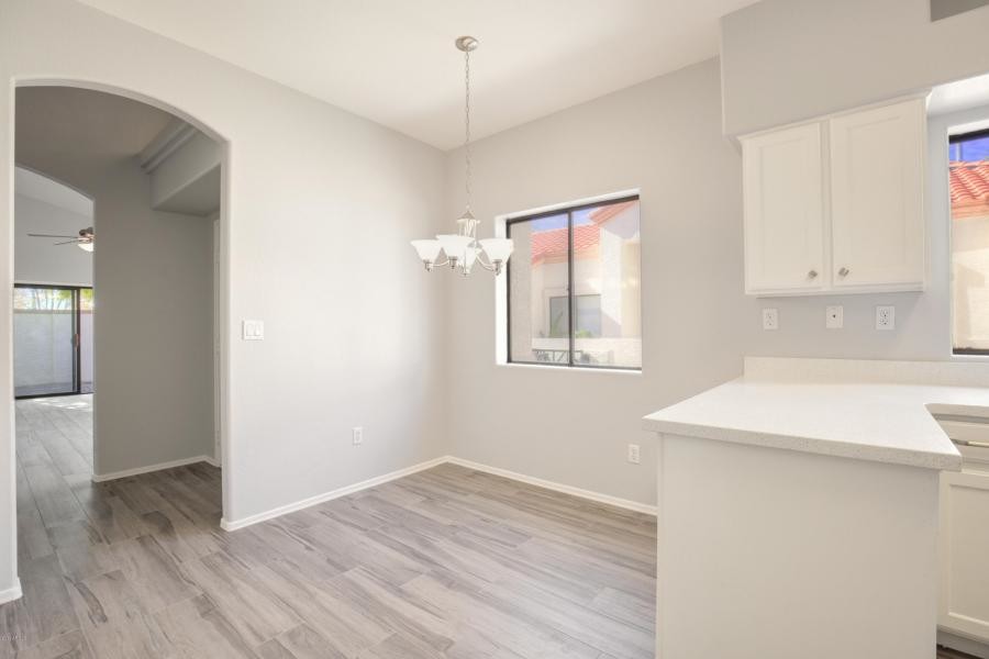 Example of a transitional u-shaped porcelain tile and gray floor eat-in kitchen design in Phoenix with an undermount sink, shaker cabinets, white cabinets, quartz countertops, white backsplash, quartz backsplash, stainless steel appliances, no island and white countertops