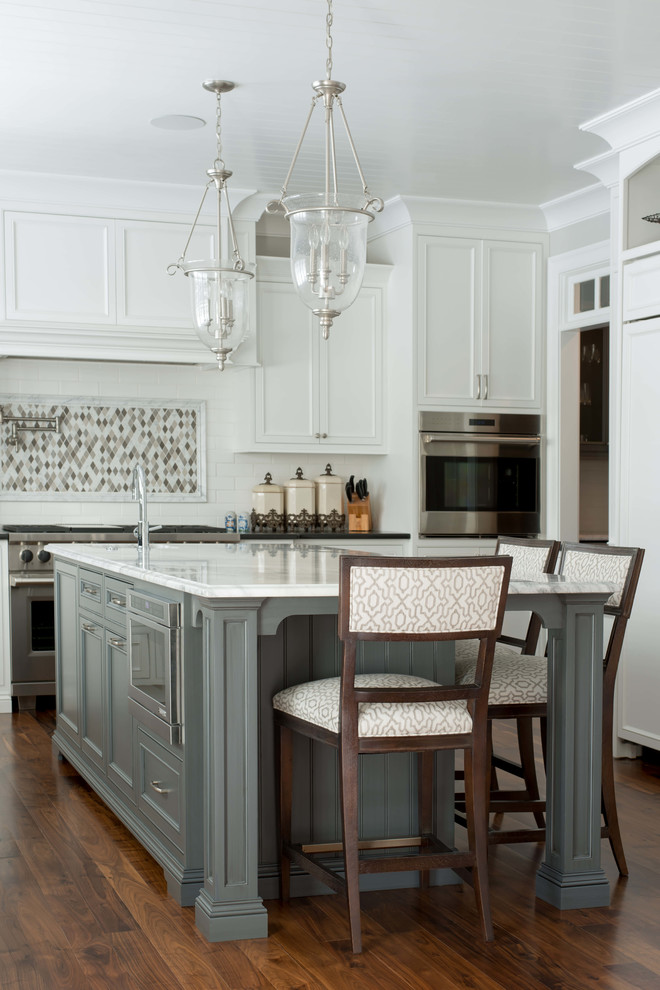 This is an example of a large traditional l-shaped eat-in kitchen in Chicago with recessed-panel cabinets, blue cabinets, marble benchtops, white splashback, subway tile splashback, stainless steel appliances, medium hardwood floors and with island.