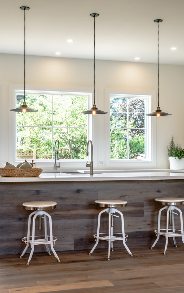 Large transitional l-shaped medium tone wood floor open concept kitchen photo in Toronto with a farmhouse sink, recessed-panel cabinets, white cabinets, white backsplash, subway tile backsplash, stainless steel appliances and an island