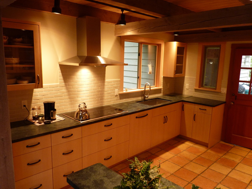 Example of a transitional galley eat-in kitchen design in Seattle with an undermount sink, flat-panel cabinets, light wood cabinets, soapstone countertops, gray backsplash, porcelain backsplash and paneled appliances