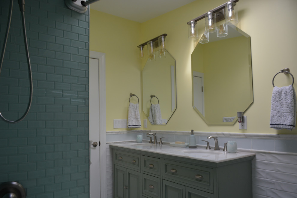 This is an example of a medium sized beach style family bathroom in New York with raised-panel cabinets, green cabinets, an alcove bath, a shower/bath combination, a one-piece toilet, white tiles, ceramic tiles, yellow walls, ceramic flooring, a submerged sink, marble worktops, white floors, a shower curtain, white worktops, double sinks, a freestanding vanity unit and a vaulted ceiling.