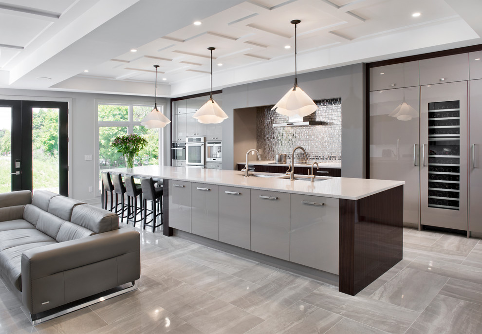 This is an example of a large contemporary kitchen in Ottawa with a single-bowl sink, flat-panel cabinets, grey cabinets, quartz benchtops, metallic splashback, mirror splashback, panelled appliances, porcelain floors and with island.