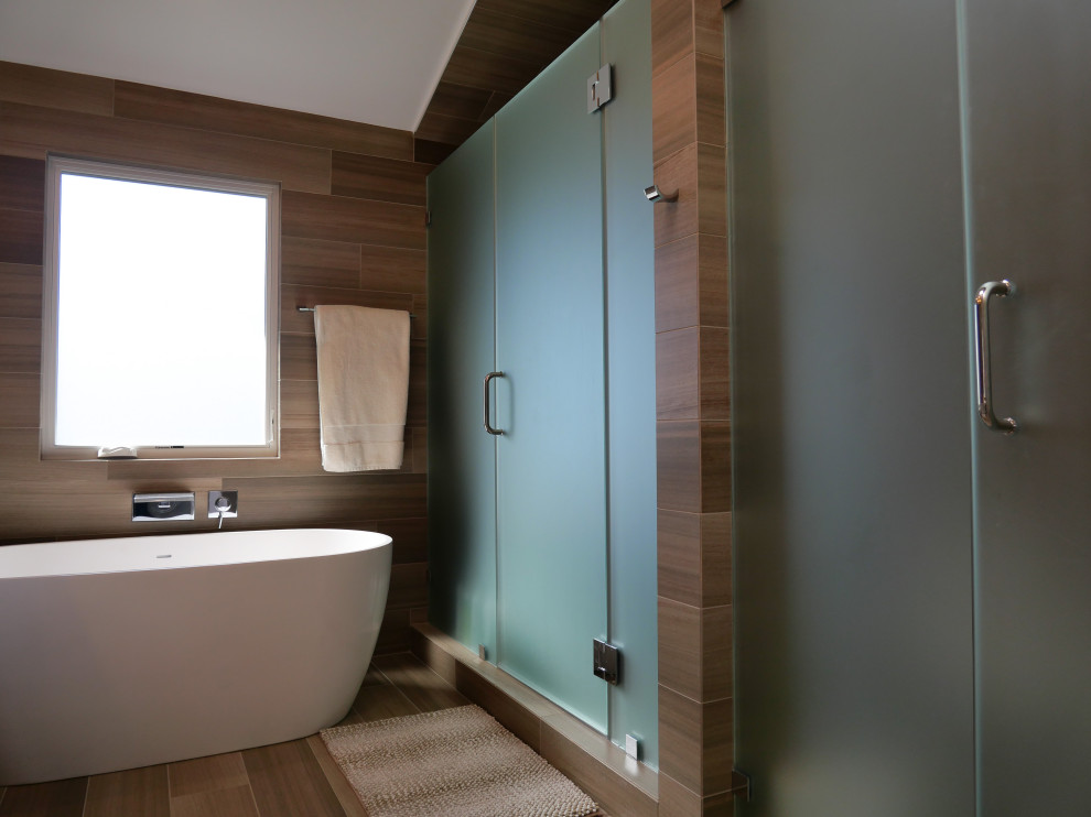 This is an example of a mid-sized modern master bathroom in Los Angeles with flat-panel cabinets, white cabinets, a freestanding tub, an alcove shower, a one-piece toilet, brown tile, brown walls, an undermount sink, quartzite benchtops, brown floor, a hinged shower door, white benchtops, an enclosed toilet, a double vanity, a built-in vanity, wood walls, porcelain tile and porcelain floors.