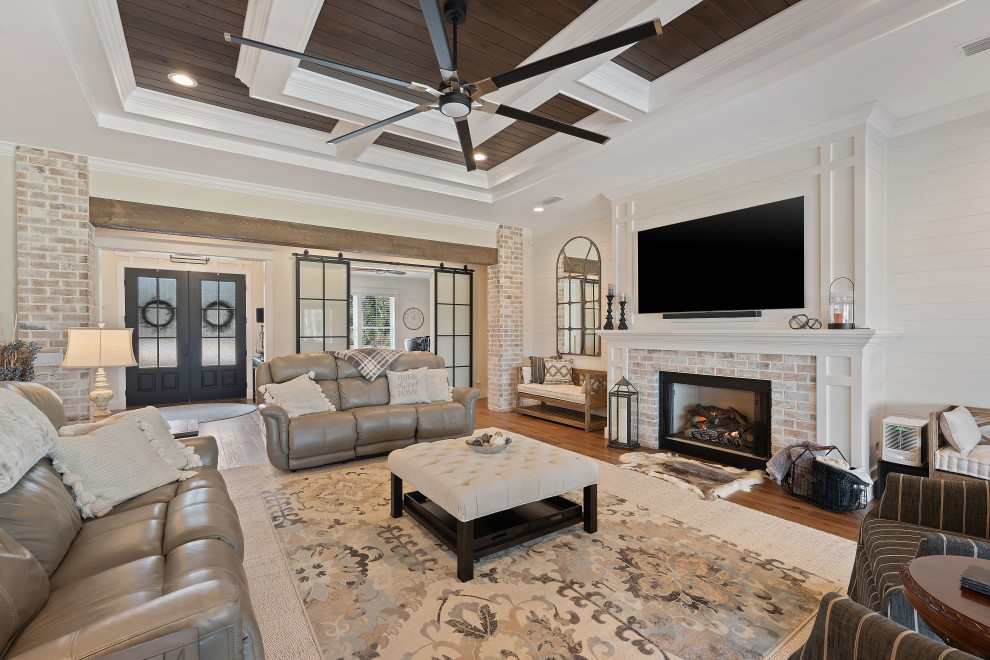 Design ideas for a large country open concept living room in Other with beige walls, medium hardwood floors, a standard fireplace, a brick fireplace surround, a wall-mounted tv, brown floor, coffered and planked wall panelling.
