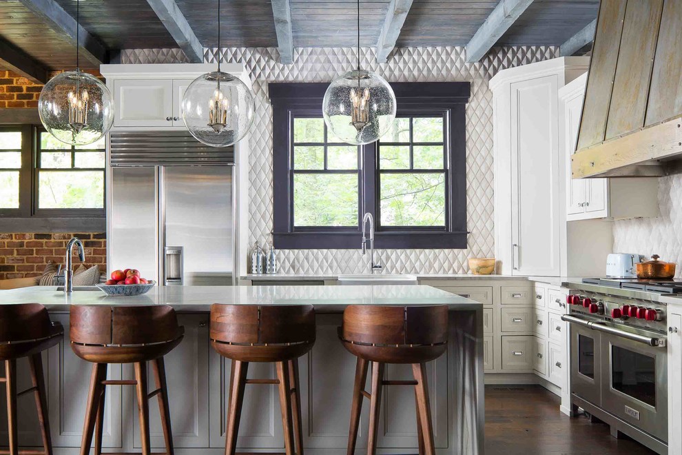 Inspiration for a country l-shaped kitchen in Atlanta with a farmhouse sink, recessed-panel cabinets, white cabinets, white splashback, stainless steel appliances, dark hardwood floors, with island, brown floor and grey benchtop.