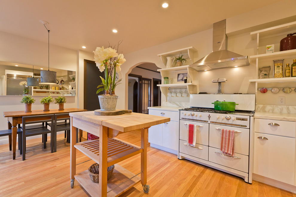 Transitional eat-in kitchen in Chicago with flat-panel cabinets, white cabinets and white appliances.