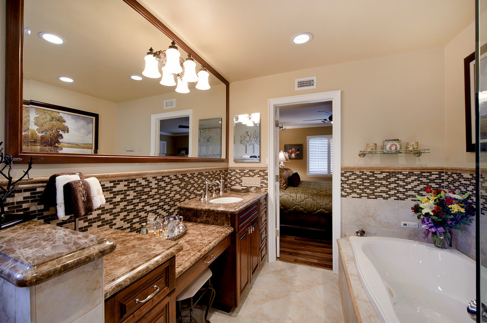 Photo of a large traditional master bathroom in Orange County with raised-panel cabinets, medium wood cabinets, a drop-in tub, an alcove shower, a one-piece toilet, multi-coloured tile, porcelain tile, beige walls, porcelain floors, an undermount sink, engineered quartz benchtops and beige floor.