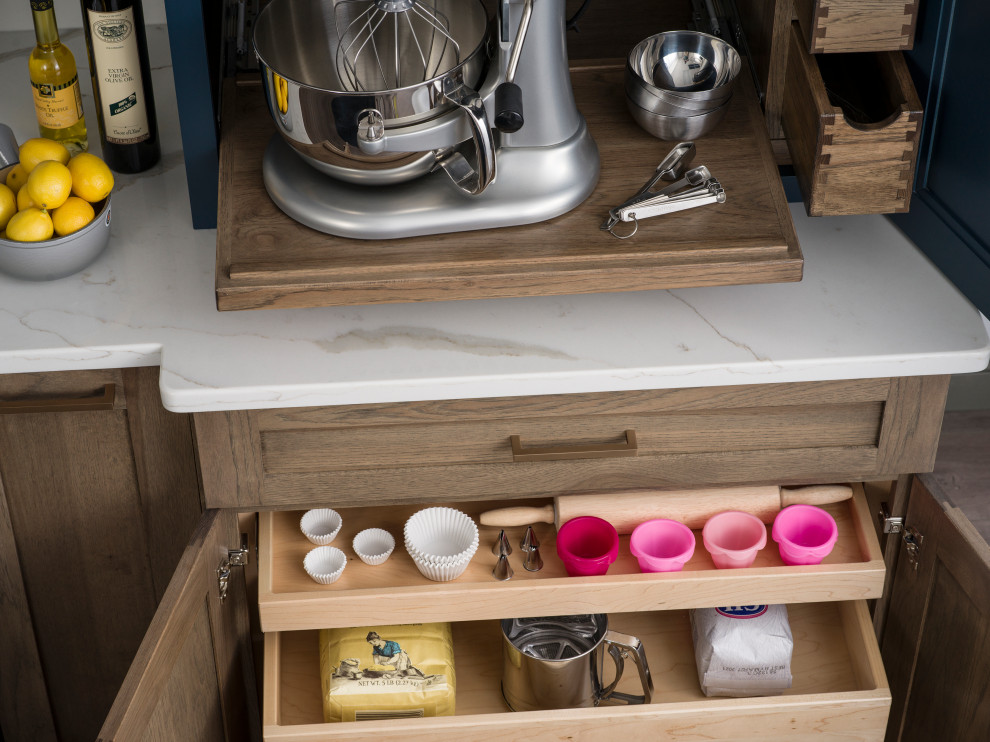 Mid-sized cottage l-shaped medium tone wood floor and brown floor open concept kitchen photo in Raleigh with a farmhouse sink, flat-panel cabinets, light wood cabinets, quartzite countertops, white backsplash, stone slab backsplash, stainless steel appliances, an island and white countertops