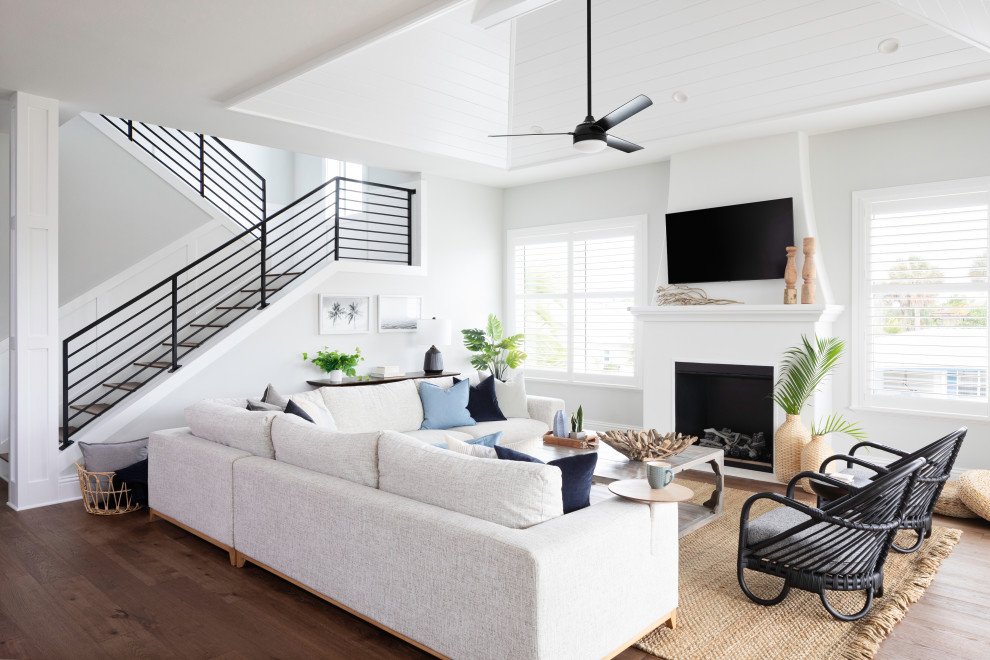 На фото: открытая гостиная комната в морском стиле с белыми стенами, паркетным полом среднего тона, стандартным камином, телевизором на стене, коричневым полом, потолком из вагонки и сводчатым потолком