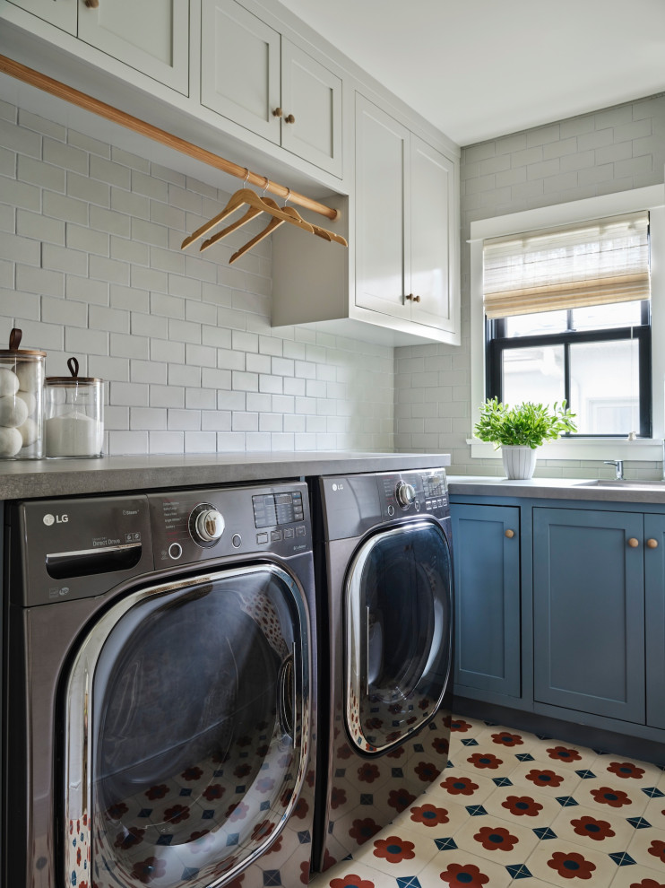 Foto di una lavanderia tradizionale con lavello sottopiano, ante in stile shaker, ante blu, paraspruzzi bianco, paraspruzzi con piastrelle diamantate, lavatrice e asciugatrice affiancate, pavimento multicolore e top grigio