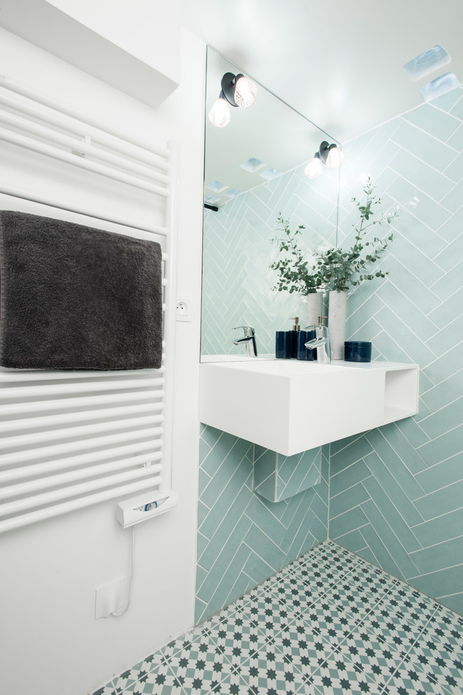 This is an example of a small scandinavian 3/4 bathroom in Paris with a curbless shower, a wall-mount toilet, blue tile, ceramic tile, white walls, ceramic floors, a wall-mount sink, solid surface benchtops, blue floor, an open shower and white benchtops.