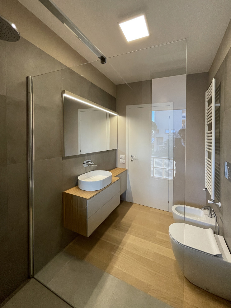 Idéer för ett mellanstort modernt brun badrum med dusch, med släta luckor, vita skåp, en kantlös dusch, en toalettstol med separat cisternkåpa, brun kakel, stenkakel, bruna väggar, mellanmörkt trägolv, träbänkskiva och brunt golv