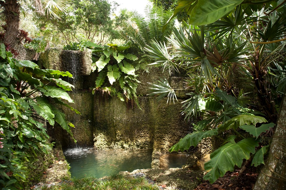 Design ideas for a mid-sized tropical backyard partial sun garden for spring in Miami with a water feature and mulch.