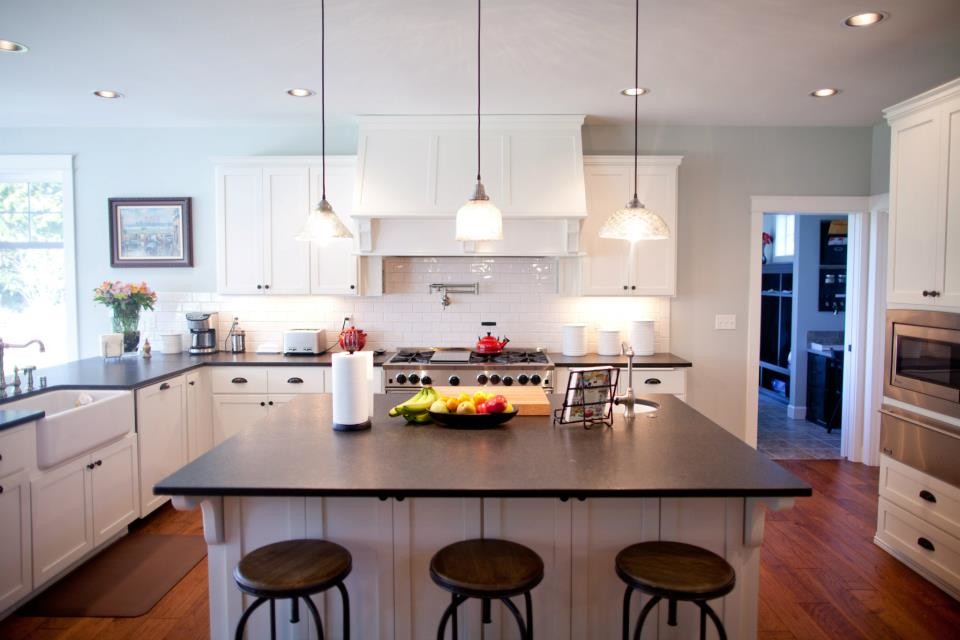 Eat-in kitchen - mid-sized transitional u-shaped light wood floor and brown floor eat-in kitchen idea in Seattle with a farmhouse sink, recessed-panel cabinets, white cabinets, granite countertops, white backsplash, subway tile backsplash, stainless steel appliances and an island