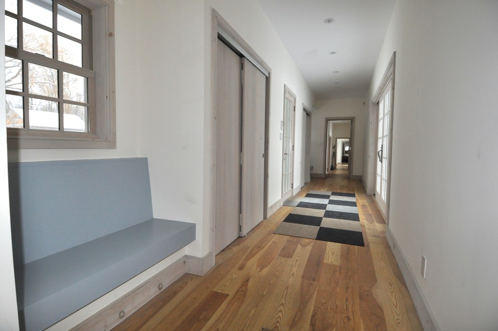 Hallway - large transitional light wood floor and beige floor hallway idea in Boston with white walls