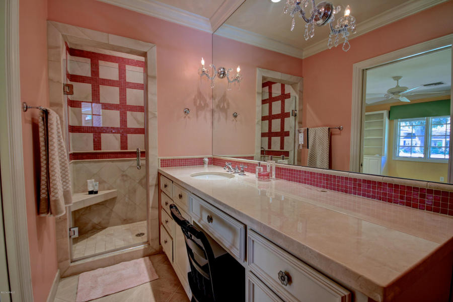 Photo of a mid-sized transitional kids bathroom in Phoenix with flat-panel cabinets, white cabinets, limestone benchtops, pink tile, an alcove shower, an undermount sink, pink walls and limestone floors.