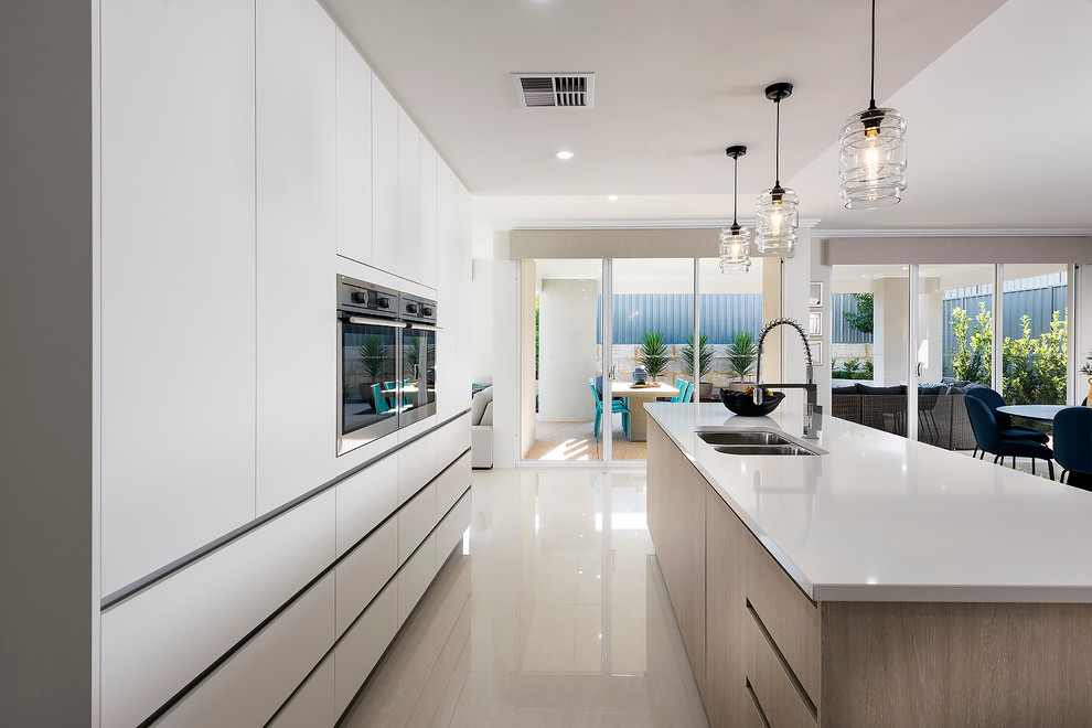 Photo of a mid-sized contemporary galley open plan kitchen in Perth with a double-bowl sink, flat-panel cabinets, white cabinets, quartz benchtops, stainless steel appliances, ceramic floors and with island.