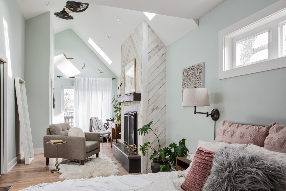 Idée de décoration pour une grande chambre parentale style shabby chic en bois avec un mur bleu, parquet clair, une cheminée standard, un manteau de cheminée en bois, un sol beige et un plafond voûté.