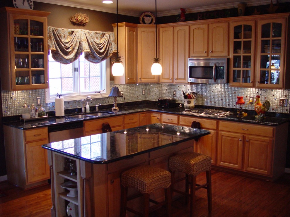 Example of a large transitional l-shaped medium tone wood floor enclosed kitchen design in DC Metro with a double-bowl sink, glass-front cabinets, light wood cabinets, granite countertops, metallic backsplash, glass sheet backsplash, stainless steel appliances and an island