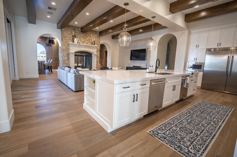 This contemporary home remodel was so fun for the MFD Team! This white kitchen features exposed wood beams, medium washed hardwood flooring, and stainless steel appliances. The open concept design spa