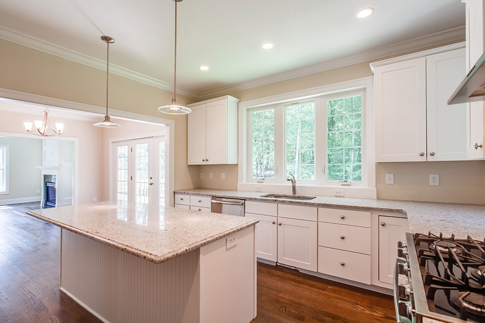 Example of a large transitional l-shaped dark wood floor and brown floor eat-in kitchen design with shaker cabinets, white cabinets, stainless steel appliances and an island