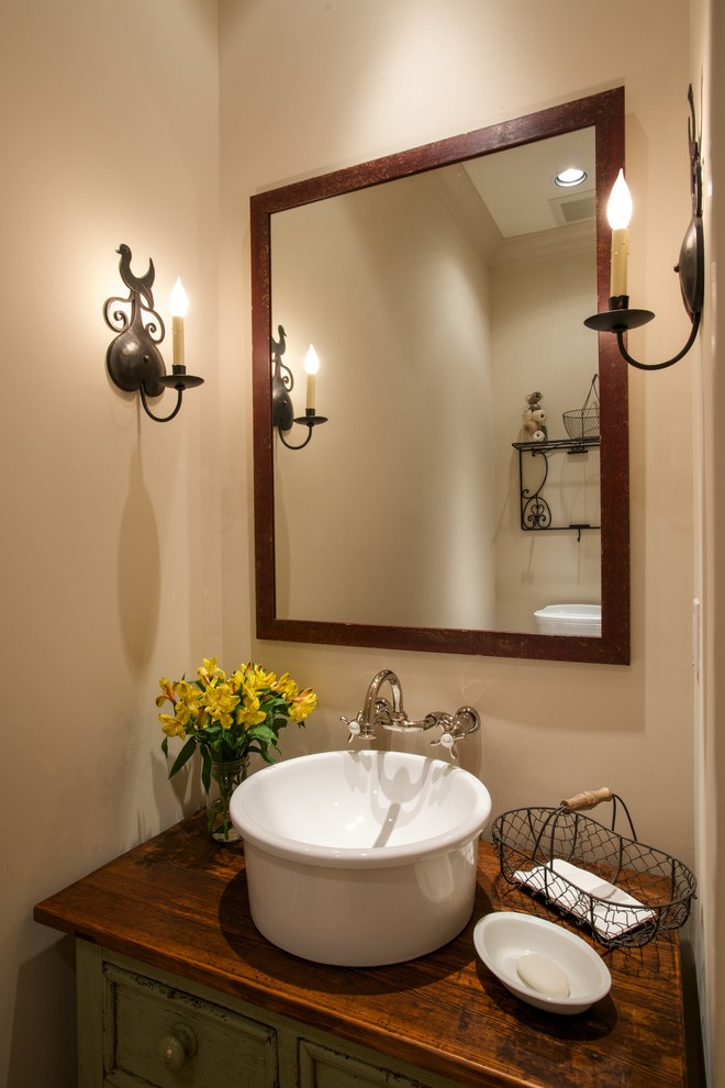 Design ideas for a small country powder room in Austin with a vessel sink, beige walls, wood benchtops, furniture-like cabinets, distressed cabinets and brown benchtops.