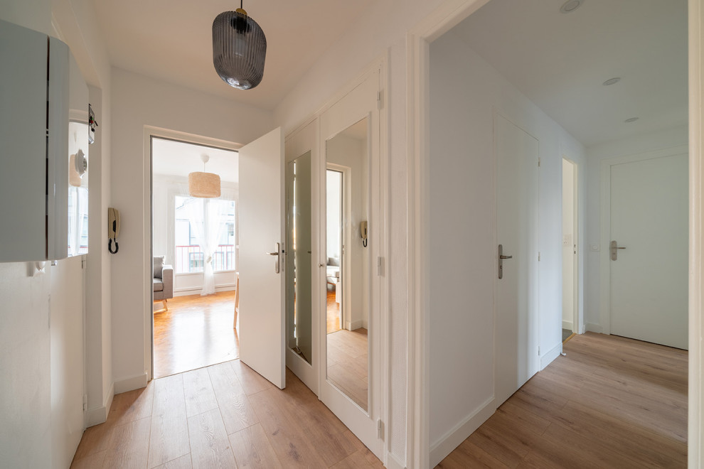 Mid-sized contemporary hallway in Nantes with white walls, medium hardwood floors and brown floor.