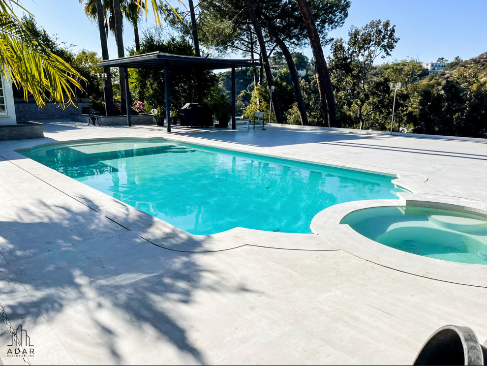 Diseño de piscinas y jacuzzis grandes a medida en patio trasero con suelo de baldosas