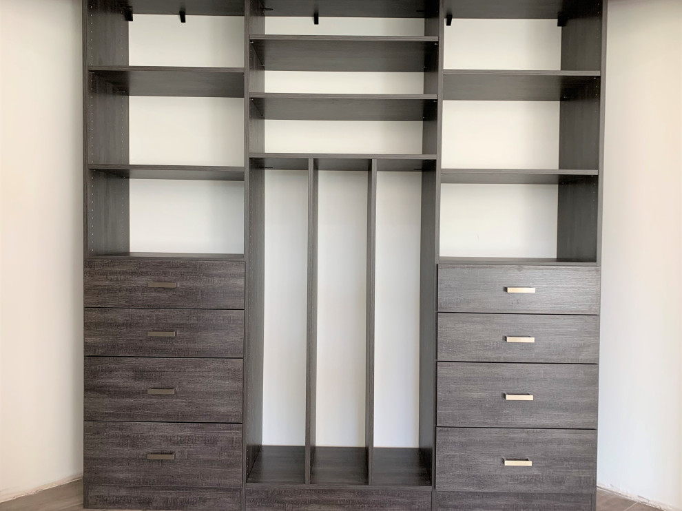 This is an example of a small contemporary gender-neutral walk-in wardrobe in Phoenix with flat-panel cabinets, black cabinets, porcelain floors and beige floor.