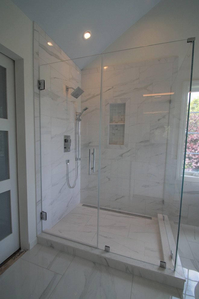 This is an example of a large traditional master bathroom in Other with shaker cabinets, white cabinets, a freestanding tub, a corner shower, a two-piece toilet, white tile, porcelain tile, white walls, porcelain floors, an undermount sink, marble benchtops, white floor, a hinged shower door, white benchtops, a niche, a double vanity, a freestanding vanity and vaulted.