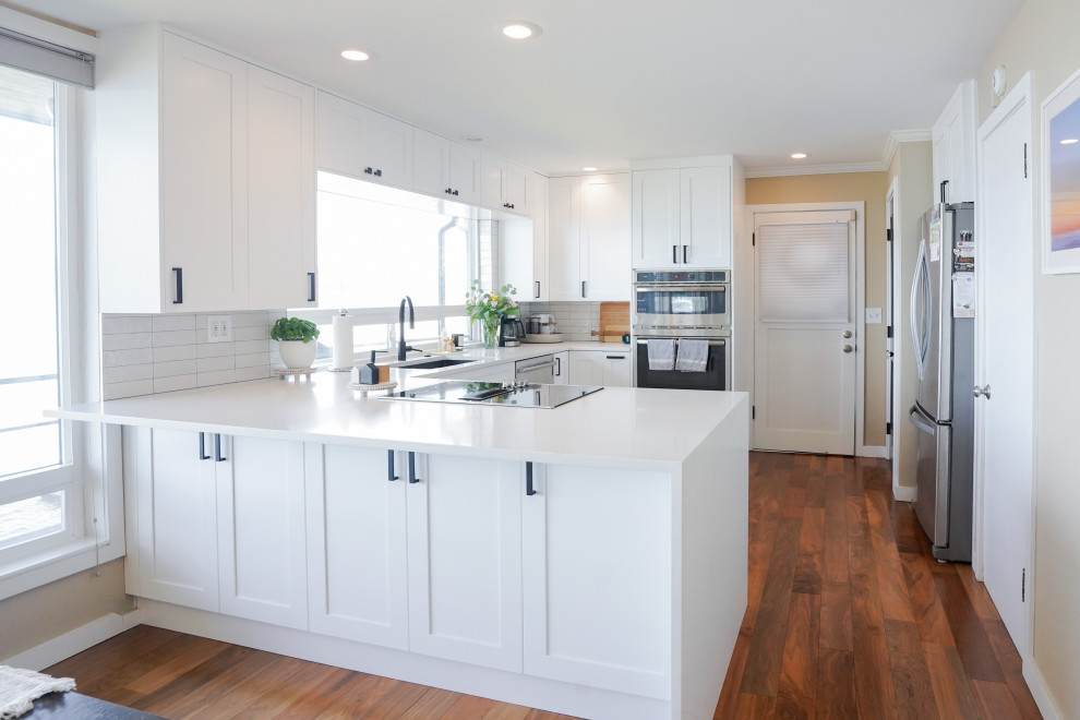 Exempel på ett litet modernt vit vitt kök, med en undermonterad diskho, vita skåp, granitbänkskiva, vitt stänkskydd, stänkskydd i keramik, rostfria vitvaror och en köksö