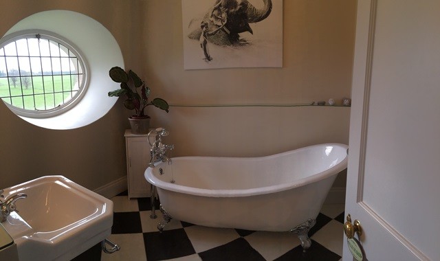 Small traditional ensuite bathroom in London with a claw-foot bath, black and white tiles, cement tiles and white walls.