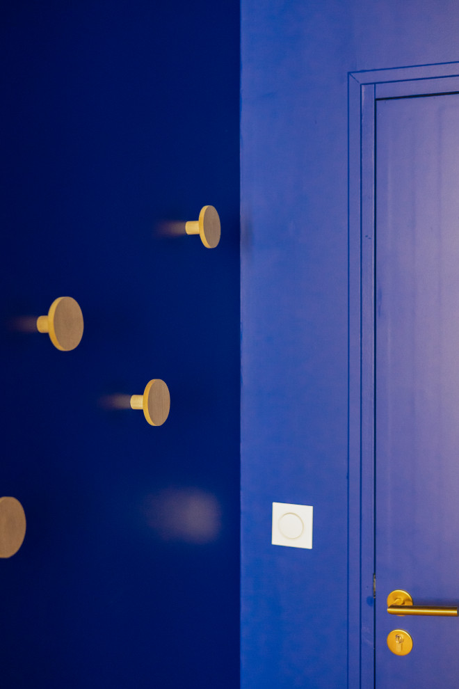 Foto di un piccolo corridoio stile marinaro con pareti blu, parquet chiaro, una porta singola e una porta blu