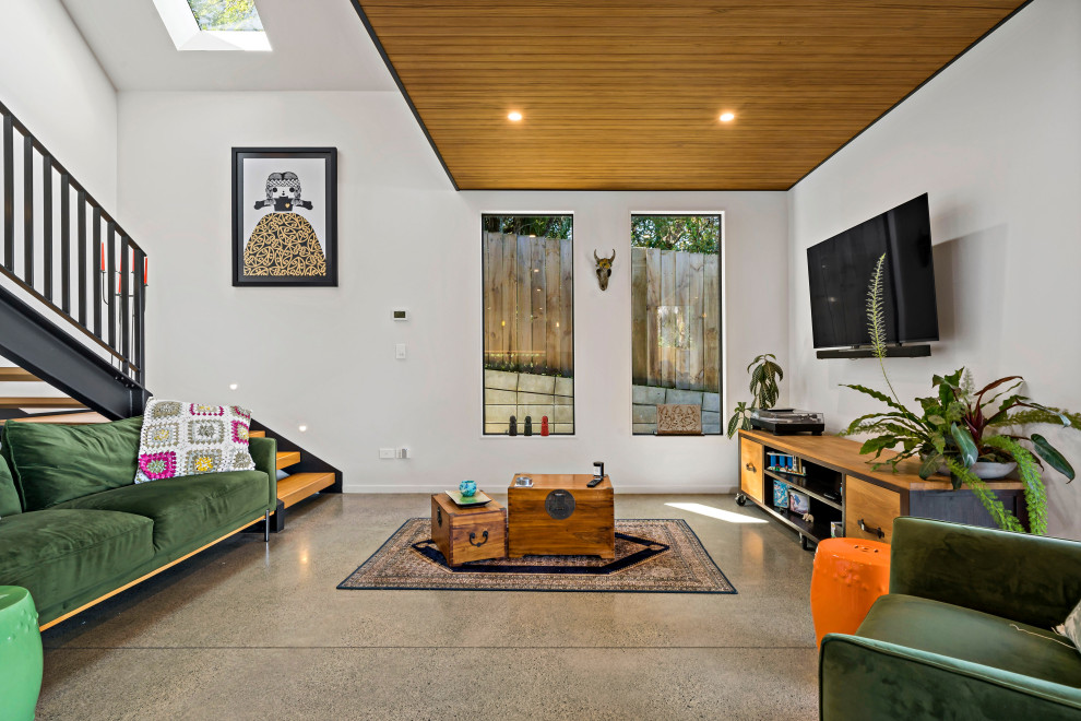 Großes Wohnzimmer im Loft-Stil mit Hausbar, weißer Wandfarbe, Betonboden, TV-Wand, grauem Boden und Holzdielendecke in Auckland