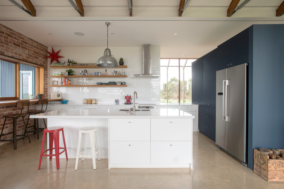 Inspiration for a contemporary l-shaped eat-in kitchen in Adelaide with an undermount sink, flat-panel cabinets, white cabinets, white splashback, stainless steel appliances, concrete floors, with island, beige floor and white benchtop.