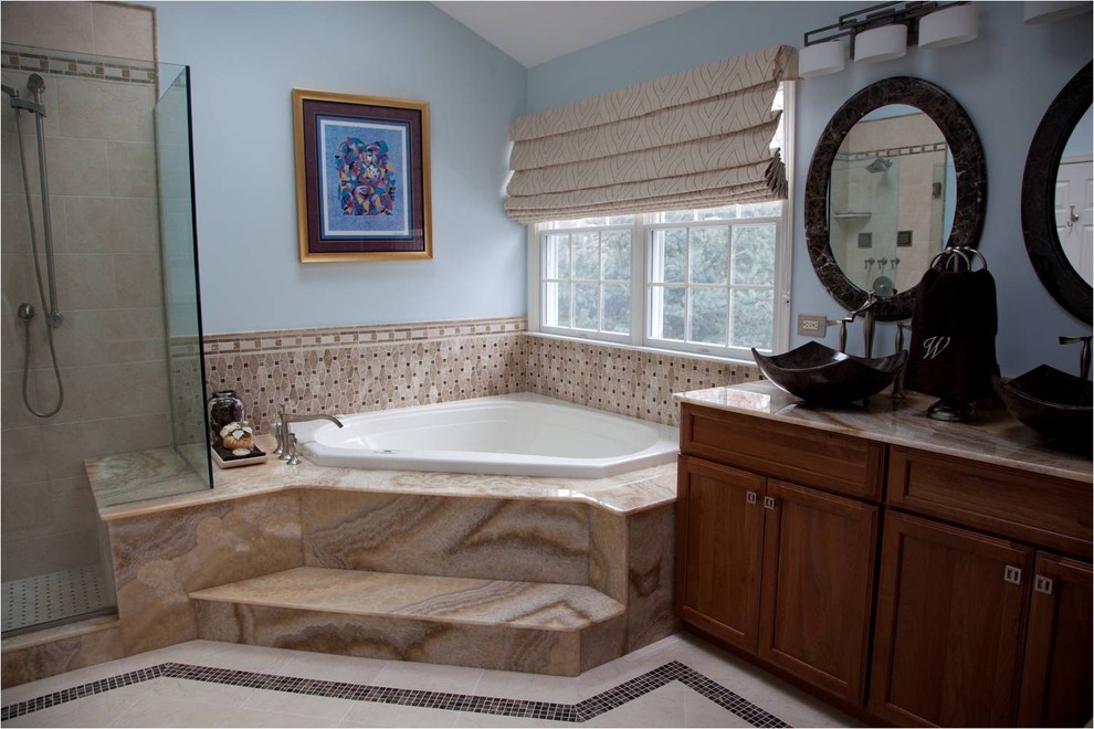 Design ideas for a large traditional master bathroom in Bridgeport with a vessel sink, recessed-panel cabinets, medium wood cabinets, onyx benchtops, a corner tub, a corner shower, a two-piece toilet, beige tile, stone tile, blue walls and marble floors.