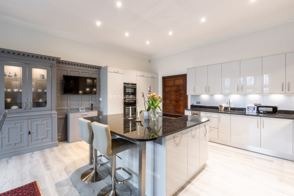 Design ideas for a large contemporary u-shaped kitchen/diner in Sussex with flat-panel cabinets, grey cabinets, granite worktops, an island, black worktops and a chimney breast.