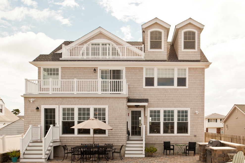 Beach style three-storey beige exterior in New York with wood siding.
