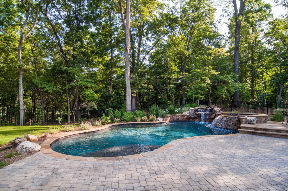 Design ideas for a mid-sized country backyard custom-shaped natural pool in Charlotte with a water feature and brick pavers.