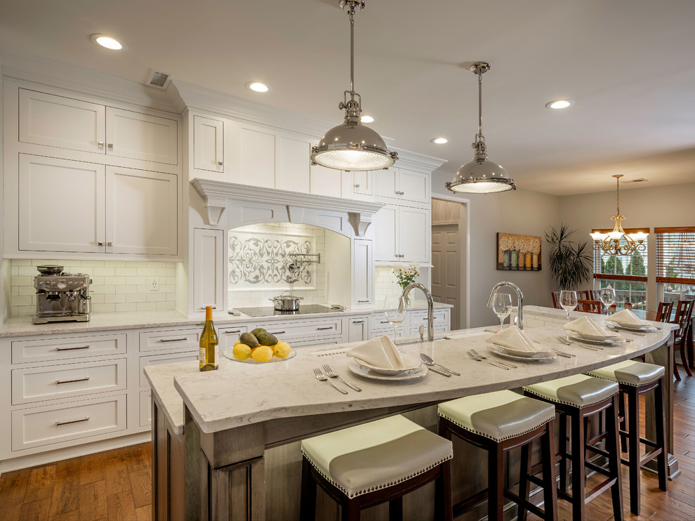 Design ideas for a mid-sized transitional kitchen in Atlanta with an undermount sink, beaded inset cabinets, white cabinets, quartzite benchtops, white splashback, subway tile splashback, stainless steel appliances, medium hardwood floors, with island, brown floor and white benchtop.