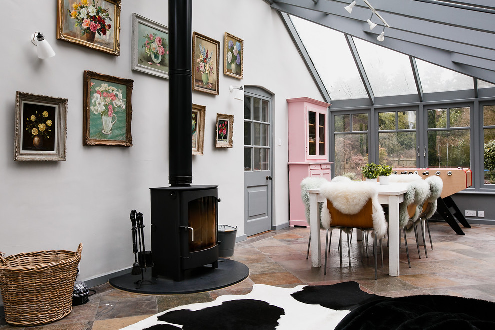 This is an example of an eclectic open plan dining in Surrey with white walls and a wood stove.