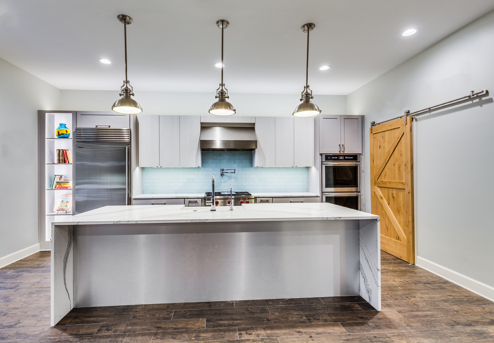 Inspiration for a mid-sized contemporary eat-in kitchen in Jacksonville with a farmhouse sink, flat-panel cabinets, grey cabinets, quartz benchtops, green splashback, glass tile splashback, stainless steel appliances, porcelain floors and with island.